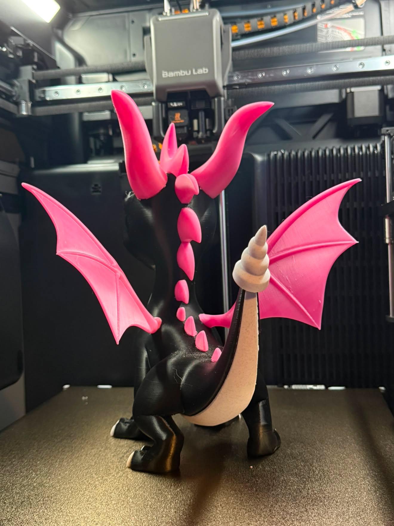 Client photo index 5: the black-and-hot-pink articulated dragon standing centred on the Bambu Lab build plate, wings spread